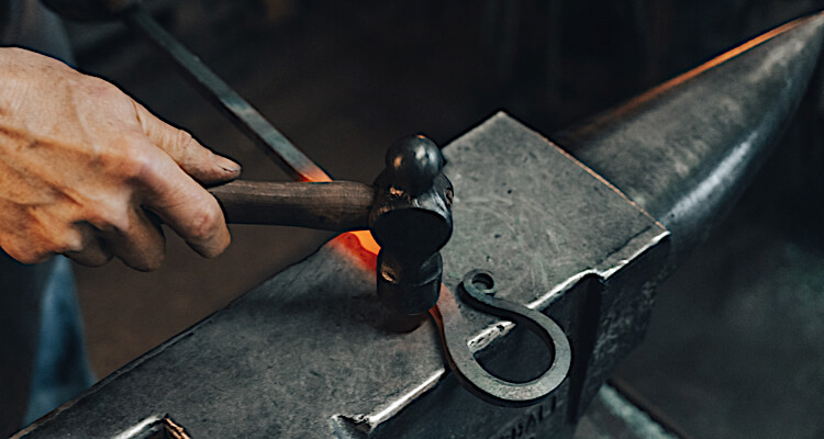 Hammering to shape wrought iron on a blacksmith workshop experience