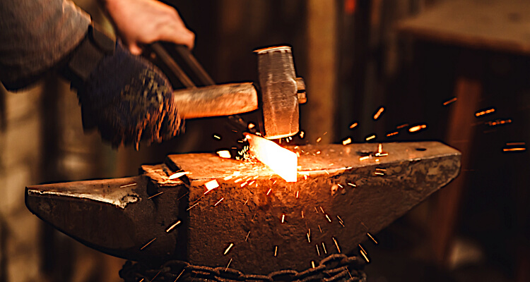 Hammering hot metal on a blacksmithing course