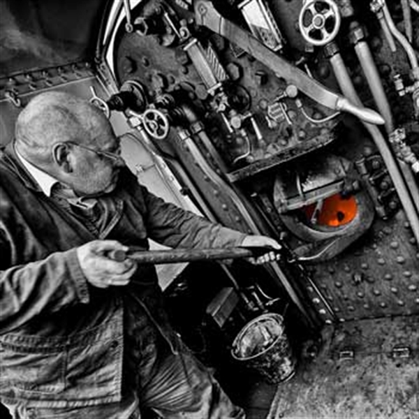 man shoveling coal into steam enginetrain driving day